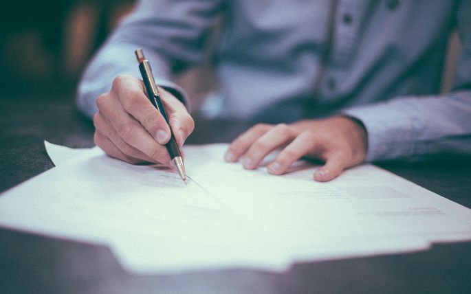seorang pria sedang menulis di atas kertas