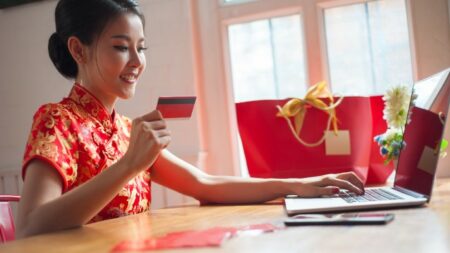 wanita tionghoa sedang belanja online di tahun baru imlek pakai kartu kredit