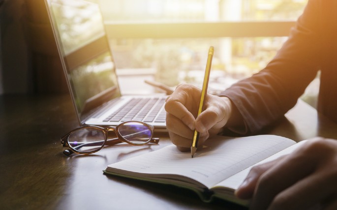 seseorang dengan buku dan laptop di meja