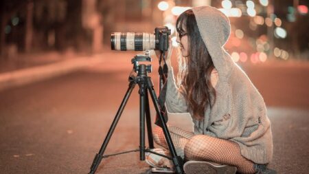 wanita memotret dengan kamera dan tripod