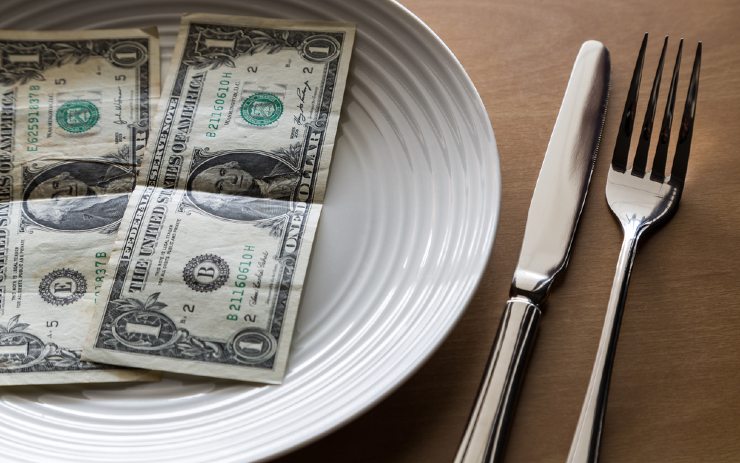 beberapa lembar dolar di atas piring dan perlengkapan makan
