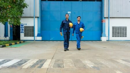 dua karyawan berjalan menjauhi sebuah pabrik
