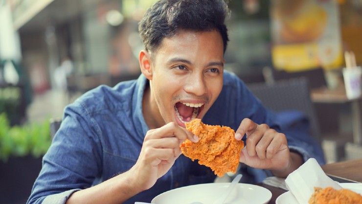 Pria makan ayam goreng (Shutterstock).