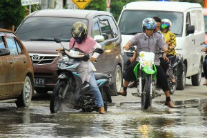 Boleh lega kalau banjir enggak tinggi sampai bikin motor mogok. Tapi hati-hati, banyak jebakan batman alias lubang yang tertutup genangan air.